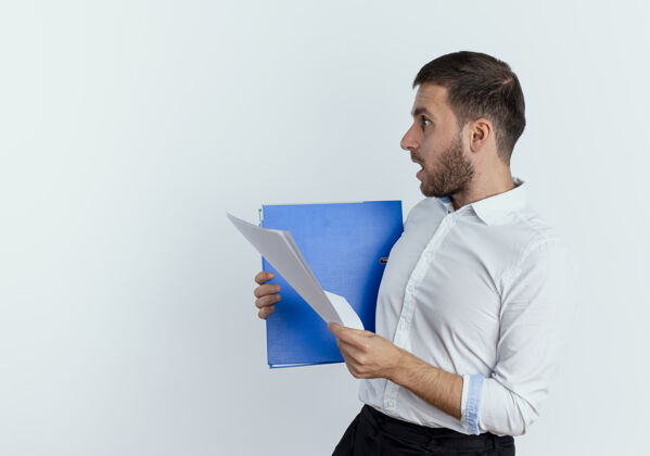 文件震惊的帅哥站在一边拿着文件夹和纸页隔离在白色的墙壁上成人立场男人