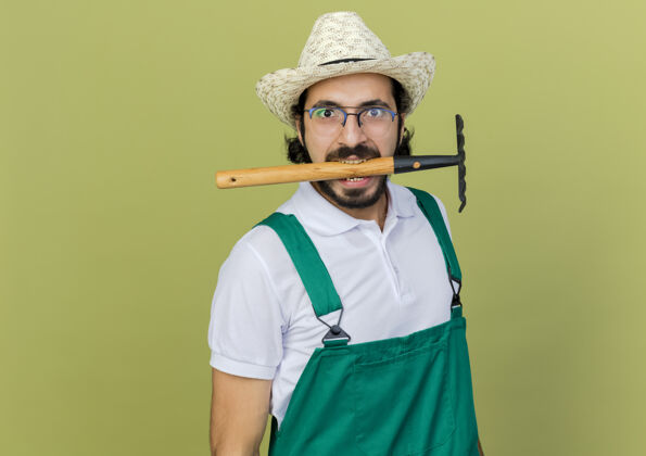 园艺滑稽的园丁戴着眼镜戴着园艺帽用牙齿拿着耙子花园空间复制