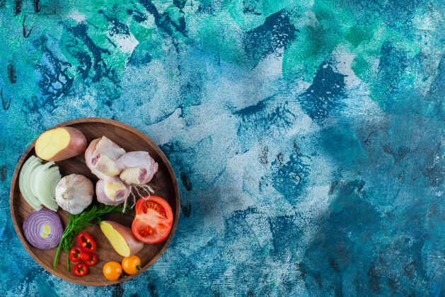 鸡肉把各种蔬菜和鸡腿放在木盘上 蓝色背景洋葱蛋白质莳萝