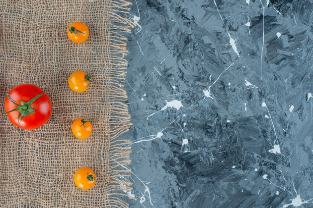 新鲜橙色西红柿和红色西红柿放在粗麻布餐巾上 大理石背景上变异番茄美味