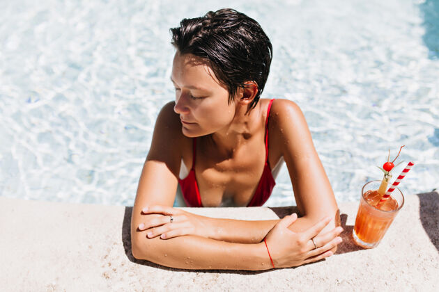 水迷人的短发女模特在泳池里享用水果鸡尾酒女性模特成人