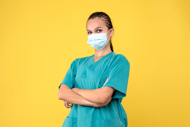 成人黄墙上穿着医疗服 戴着无菌口罩的女医生的正面图绝育脸套装