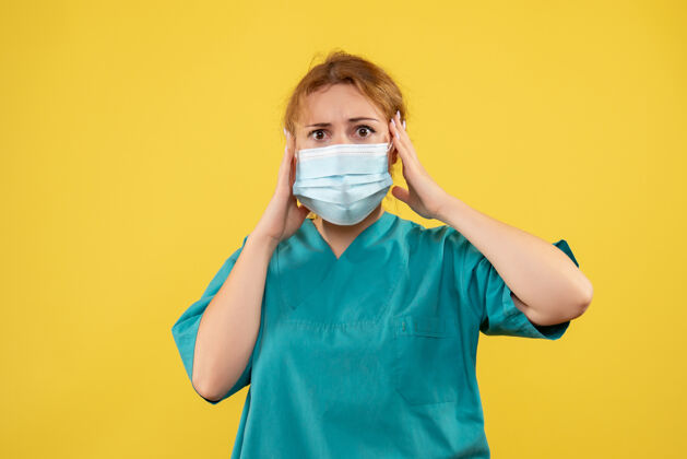 漂亮黄墙上年轻女医生穿着医疗服 戴着口罩的正面图健康面具成人