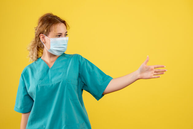 医疗黄墙上穿着医疗服 戴着无菌口罩的女医生的正面图肖像套装人