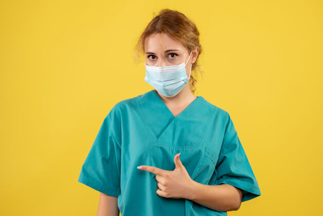 人黄墙上年轻女医生穿着医疗服 戴着口罩的正面图护士套装健康