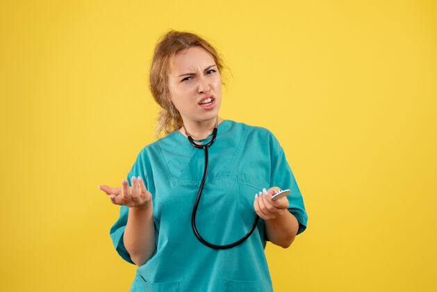 情绪黄色墙壁上穿着医疗服 带听诊器的女医生的正视图医生医疗困惑