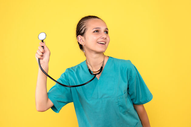 医疗黄色墙上穿着带听诊器的医用衬衫的女医生的正视图女医生护士衬衫