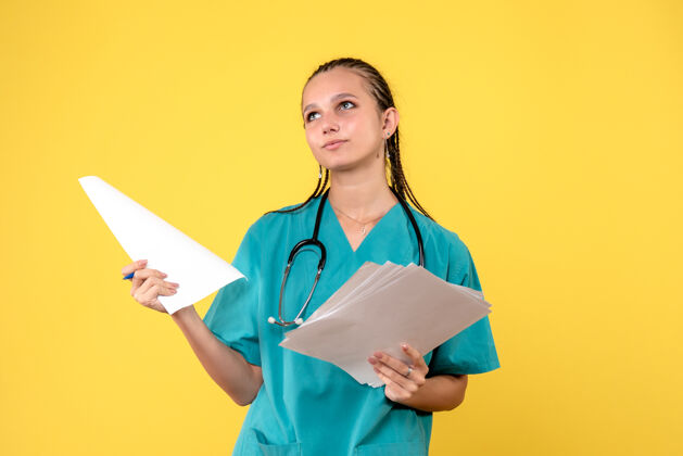 护士身着医疗服的女医生的正面图 黄色的墙上有纸医院人健康