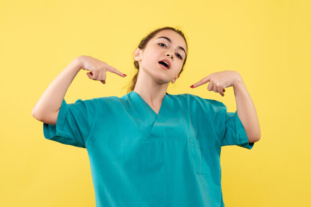 医学黄色墙壁上穿着医疗服的女医生的正视图套装健康医院