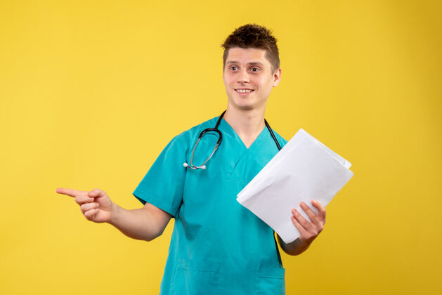 微笑黄色墙壁上的男医生穿着医疗服的正面图医学病毒情绪