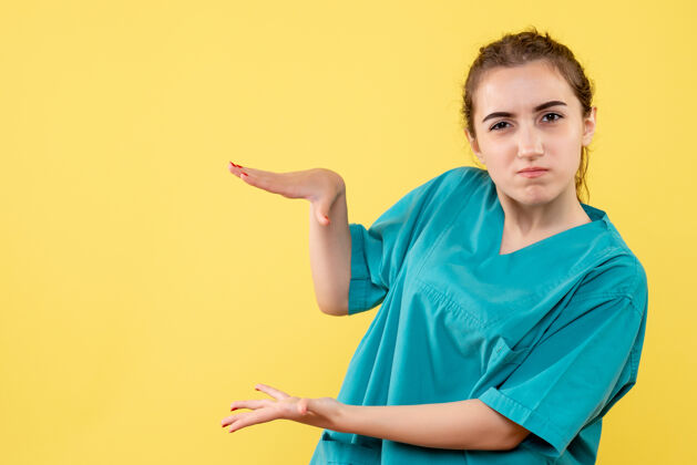 肖像黄墙上年轻女医生穿着医用衬衫的正面图疾病医学医院