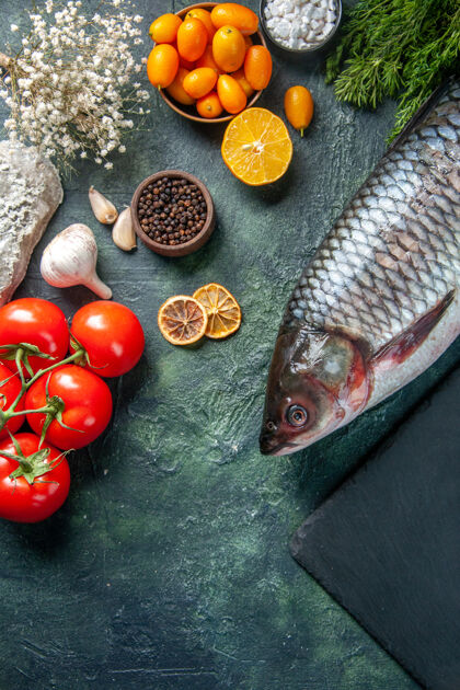 饮食顶视图新鲜的生鱼与西红柿和绿色的深色背景牛仔裤鱼西红柿