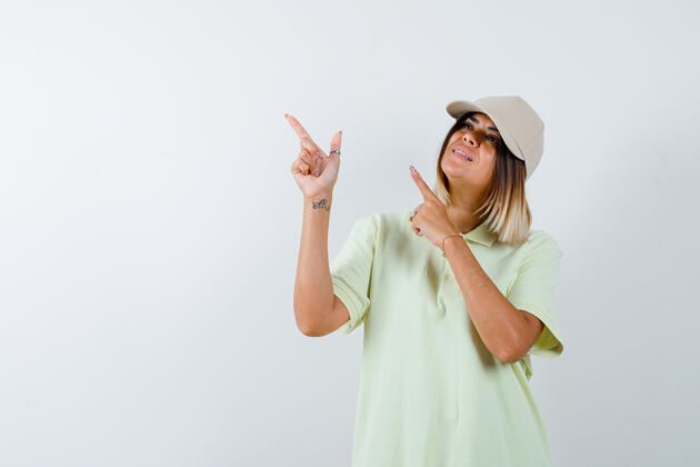 年轻穿着t恤的年轻女士 戴着帽子指着左上角 看上去很高兴 正前方的景色水疗时尚自然