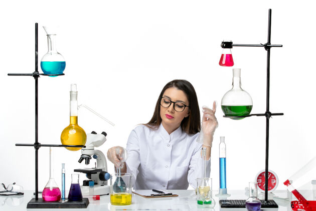 实验室前视图穿着白色医疗服的女化学家拿着装有蓝色溶液的烧瓶 背景是浅白色的实验室科学病毒冠状病毒大流行医学溶液大流行