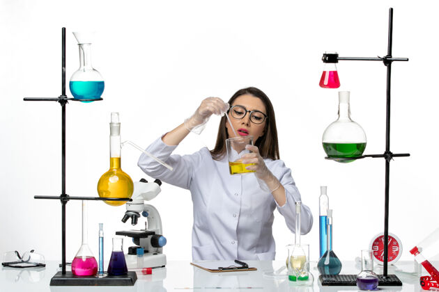 病毒前视图穿着医疗服的女化学家在白色背景上工作的解决方案实验室病毒冠状病毒-大流行科学实验室葡萄酒前面