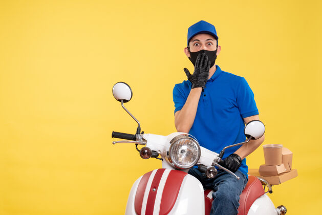 男人正面图男性快递员戴着黄色大流行快递工作服戴着口罩坐在自行车上摩托车传送带男性