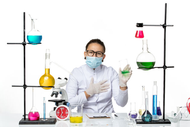 科学前视图穿着医疗服的女化学家 戴着面罩 白色背景上有绿色溶液 飞溅实验室病毒化学covid-实验室解决方案实验室