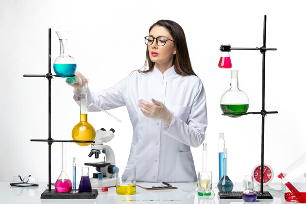 正面前视图身着医疗服的女化学家正在用浅白色背景的解决方案研究实验室病毒冠状病毒-大流行科学解决方案人实验室