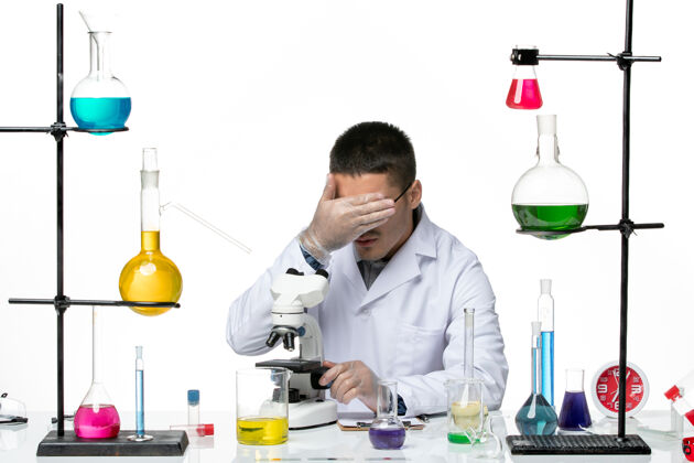 医生前视图男性化学家穿着白色医疗服 在白色背景上用显微镜观察病毒冠状病毒-疾病实验室科学医学病毒实验室