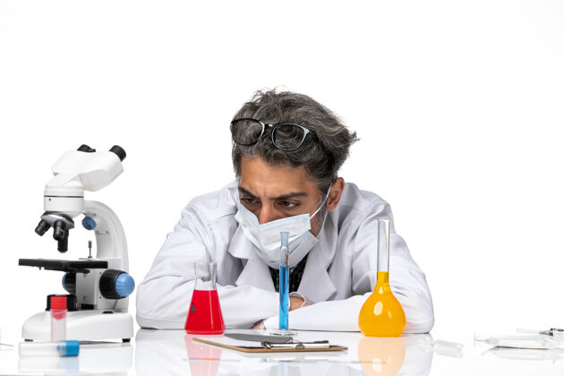 坐正面近距离观察穿着特殊套装的中年科学家坐在白色背景上 拿着溶液男性病毒科学冠状病毒-化学医院病毒专业