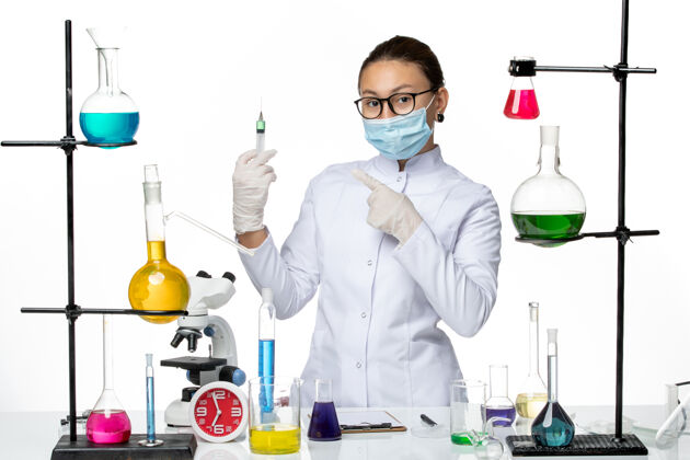 病毒前视图：穿着医疗服的女化学家 戴着面罩 在浅白色背景上拿着注射液病毒化学实验室covidsplash注射实验室西装