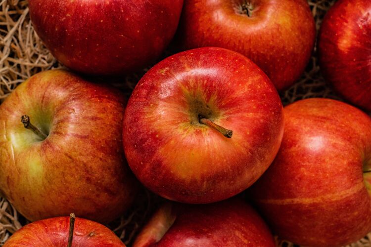 配料干草表面上一堆看起来很好吃的红苹果的特写镜头新鲜草多汁的