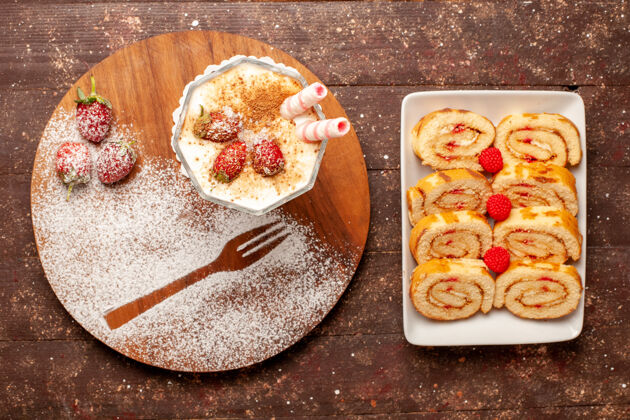 木头俯瞰美味的草莓甜点和甜水果卷在棕色的木制书桌上桌子晚餐盘子