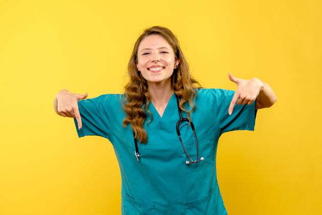 药黄色墙上微笑的女医生的正面图女人制服保健
