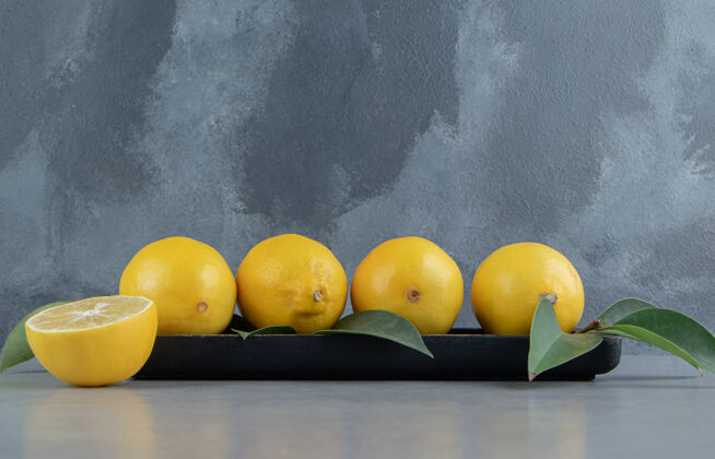 配料柠檬放在一个小托盘上 上面装饰着大理石上的叶子饮食叶多汁