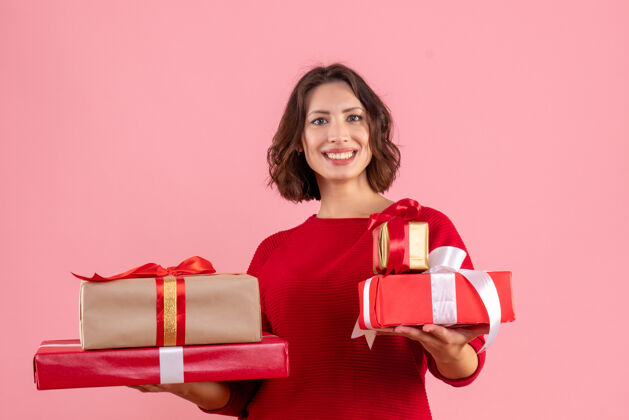 正面正面图：年轻女性手持粉色圣诞礼物颜色风景微笑