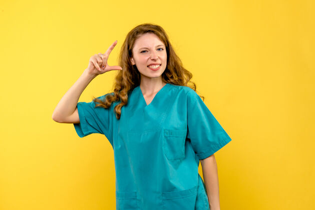 成人黄色墙上微笑的女医生的正面图专业女医生正面