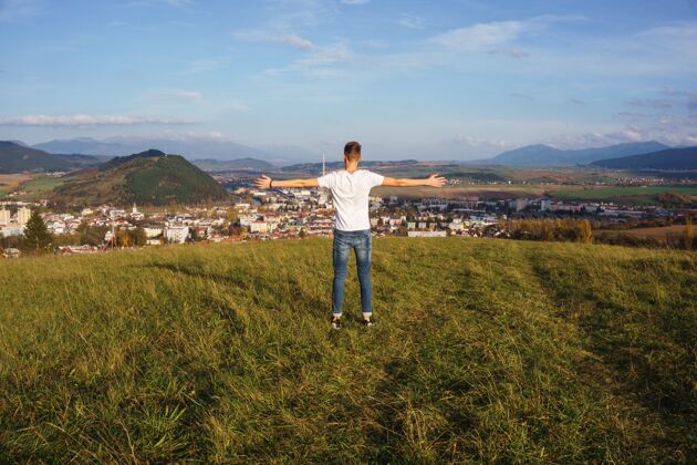 阳光一个男人张开双臂站在山上 骄傲地看着他的家乡自然骄傲堡垒