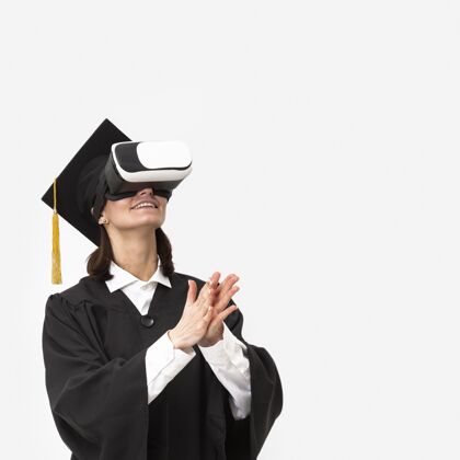 毕业穿着毕业礼服戴毕业帽戴着虚拟现实耳机的女人虚拟现实耳机虚拟现实模特