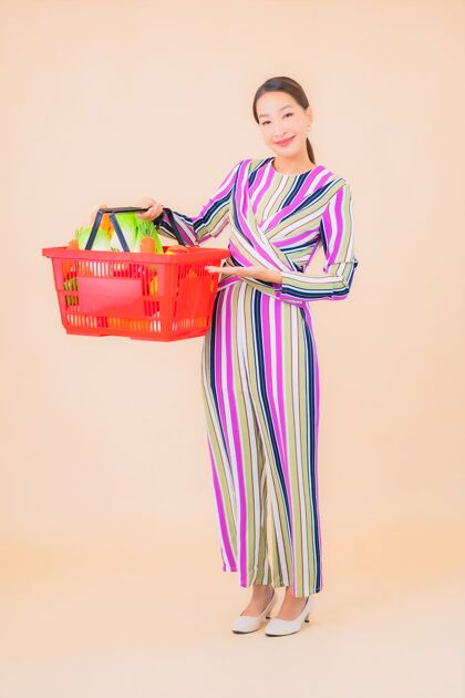女人一幅美丽的亚洲年轻女子的肖像画 上面是超市的购物篮健康消费者购买