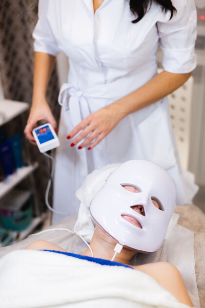 女人客户躺在美容桌上的沙龙里 脸上戴着白色的面具成人水疗皮肤科
