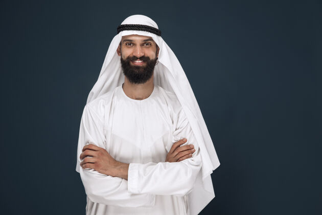 迪拜深蓝色工作室背景上的半身阿拉伯沙特商人肖像年轻男模站着微笑商业 金融 面部表情 人类情感的概念惊讶肖像兴奋