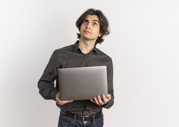 年轻年轻困惑英俊的白种人拿着笔记本电脑 在白色背景上孤立地抬头看 还有复印空间笔记本电脑迷茫帅气