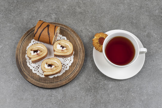甜点在木板上放几片甜甜的蛋糕和一杯茶奶油热的杯子