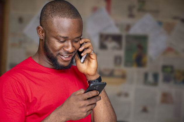 讨论年轻的非洲男性一边在房间里用另一个电话一边打电话微笑年轻表情