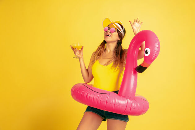 手势在沙滩上摆出鸡尾酒会的姿势黄色背景上的白种女人肖像戴帽子的漂亮女模特人类情感的概念 面部表情 销售 广告夏日 旅游 度假夏天情感工作