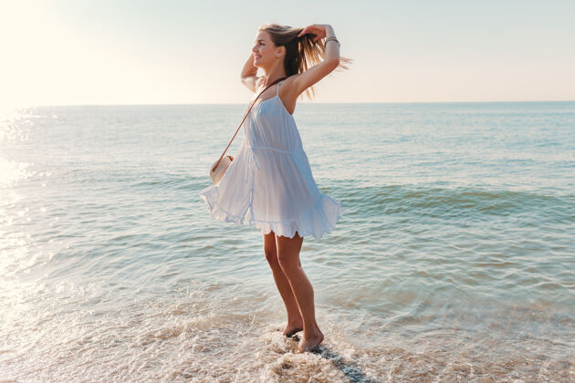 日出年轻迷人的快乐女子在海边转悠阳光明媚的夏日时尚风格热带手臂阳光
