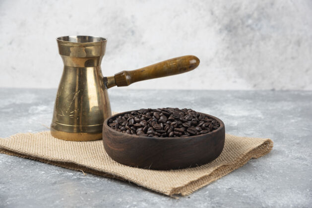 香味一个木制的碗 上面放着深烤咖啡豆和咖啡机 放在大理石表面上美食农作物