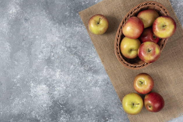 顶视图柳条篮成熟闪亮的苹果在大理石表面自然营养美味