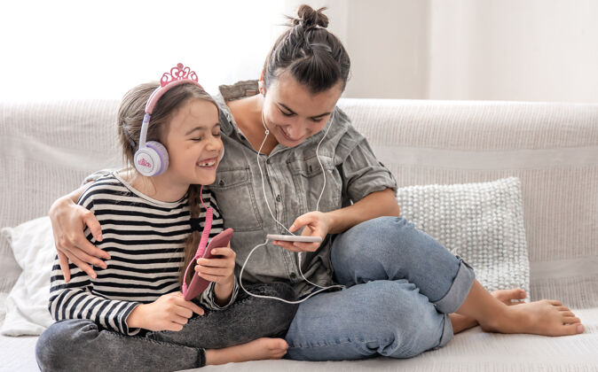 美好时光欢快的母女俩正在家里休息 戴着耳机听音乐休闲家庭女儿