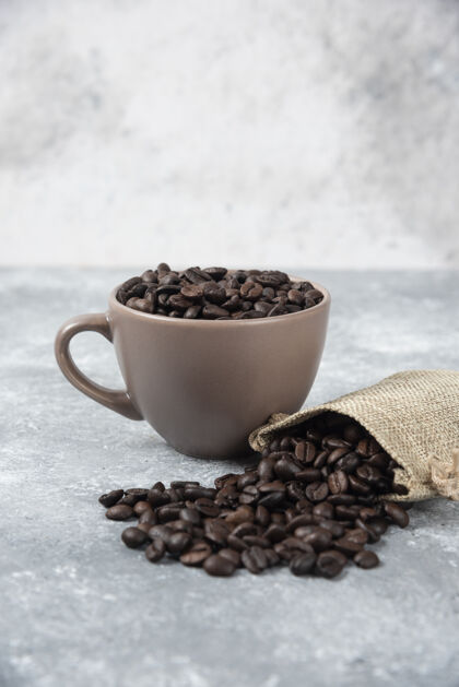 咖啡把咖啡豆从粗麻袋中取出 放在大理石上的杯子里粗麻布陶瓷自然
