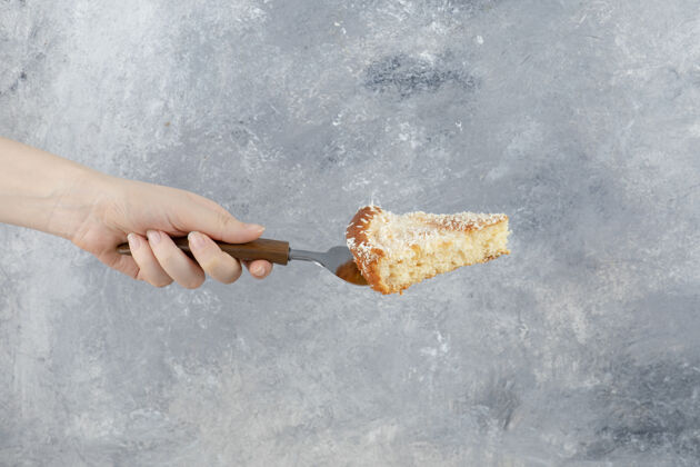 糕点在大理石背景上拿着甜馅饼的女人的手美味切片焦糖