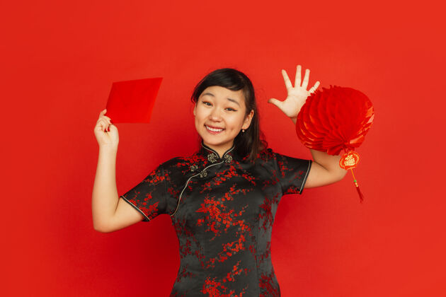 庆祝2020年中国新年红色背景上的亚洲少女肖像穿着传统服装的女模特看起来很高兴装饰和红包庆祝 节日 情感新服装祝福