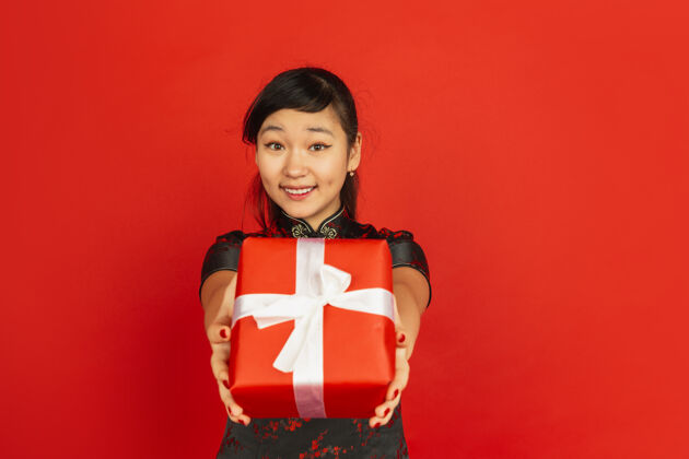 女孩赠送礼品盒2020中国新年快乐红色背景上孤立的亚洲少女肖像穿着传统服装的女模特看起来很快乐庆祝 节日 情感复制空间手服装照明