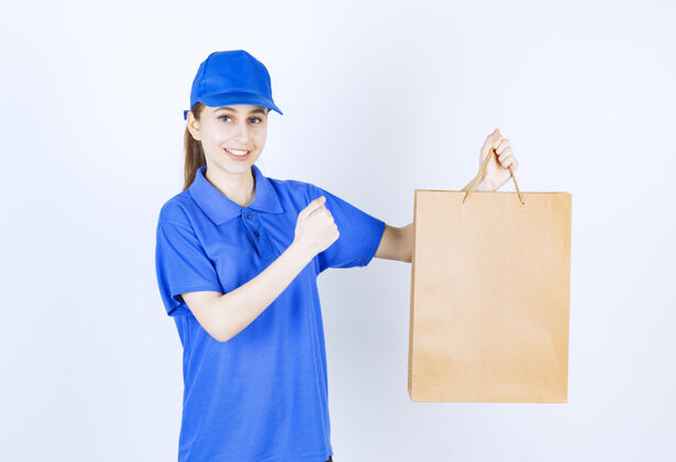 服务穿着蓝色制服的女孩手里拿着一个纸板购物袋 伸出拳头人人成就