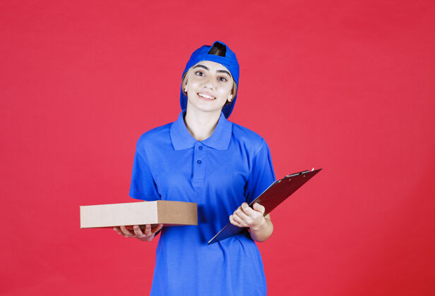 送货穿着蓝色制服的女快递员手里拿着一张清单和一个外卖箱年轻人成人聪明